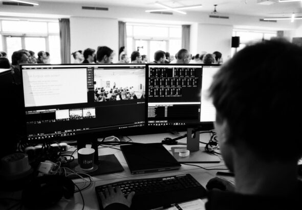 a man sitting at a desk with several monitors