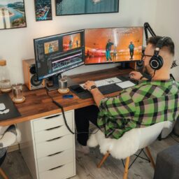 a person sitting at a desk with a computer and a dog