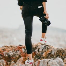 woman in black shirt and black pants holding black dslr camera