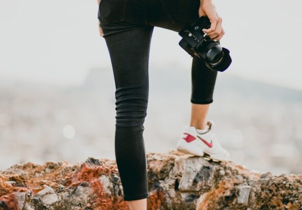 woman in black shirt and black pants holding black dslr camera